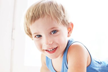 Pencere pervazına, perdenin arkasındaki saklambaç oynamaktan oturan sevimli küçük sarışın çocuk. Eğlenceli, gülümseyen ve gülen olan mutlu çok güzel üç yaşındaki çocuğun portresi. Arka plan, yakın çekim, alanı Kopyala.