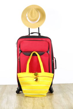 Tek kırmızı dayanıklı Tekstil Bagaj kadın hasır şapkalı genişletilmiş teleskop sapı, sarı plaj çantası ve güneş gözlüğü üzerinde asılı. Tatil gezisi için hazırlanmış bir bavul. Beyaz arka plan, kopya alanı.