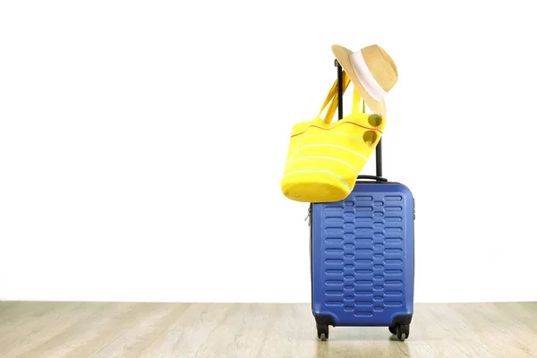 单蓝色塑料硬壳行李与妇女的草帽悬挂在扩展伸缩手柄 黄色沙滩袋 太阳镜 一个手提箱准备度假旅行 白色背景 复制空间 — 图库照片