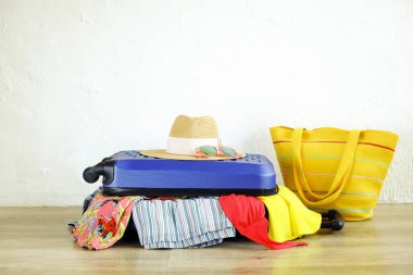 İn yakın elbise yapışkanlık dışarı şeyler dağınık tam dolu kapalı çantada uygun değil. Mavi sert kabuklu Bagaj. Plaj çanta, şapka, güneş gözlüğü. Kadın tatil kavramı için ambalaj. Alan arka plan kopyalama