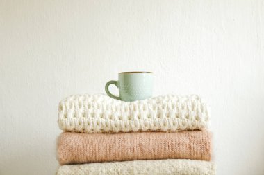 Fincan cappuccino kahve w / farklı örgü modelleri örgü sıcak pastel renk kazak demet ikiye katlanmış. Sonbahar Kış Triko giyim. Dokulu duvar arka plan. Yakın çekim, alanı Kopyala.