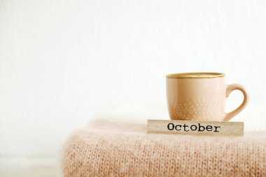 Word ahşap takvim, cappuccino kahve, sıcak örme kazak görünür örgü modelleri ile yazılı Ekim katlanmış. Sonbahar Kış sezonunda Triko giyim. Arka plan, yakın çekim, alanı Kopyala.