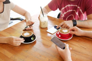 Grup arkadaşıyla cappuccino kahve dükkanında içme seviyor ve iletileri kontrol smartphones vasıl bakıyordu. Sosyal medya bağımlılığı. Genç erkekler ve kadınlar cep telefonları ve içecekler tutarak. Arka plan, üstten görünüm.