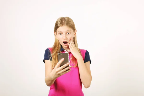 年轻的女子穿着黄色蓝色棒球衫 在手机上收到令人惊讶的短信 张开嘴巴 惊讶的金发少女与智能手机 复制空间背景 — 图库照片