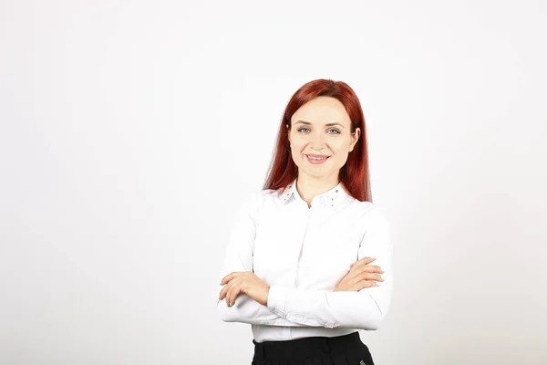 Beautiful businesswoman wearing formal wear, black skirt & white blouse standing with arms folded on chest. Attractive woman with red hair and make up, hands crossed. Copy space background, close up.