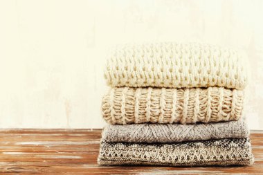 Örme sıcak pastel renk Kazak farklı örgü modelleri ile demet yığın kahverengi ahşap masa, grunged doku duvar arka plan üzerinde katlanmış. Sonbahar Kış sezonunda Triko. Yakın çekim, alanı Kopyala