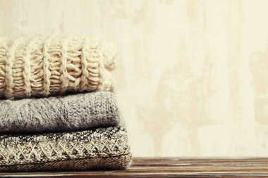 Örme sıcak pastel renk Kazak farklı örgü modelleri ile demet yığın kahverengi ahşap masa, grunged doku duvar arka plan üzerinde katlanmış. Sonbahar Kış sezonunda Triko. Yakın çekim, alanı Kopyala