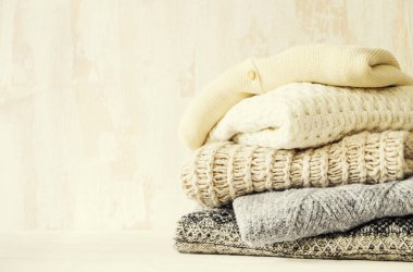 Örme sıcak pastel renk kazak, örgü desenleri dağınık yığın kahverengi ahşap masa, grunged doku duvar arka plan üzerinde katlanmış farklı grup. Sonbahar Kış sezonunda Triko. Yakın çekim, alanı Kopyala