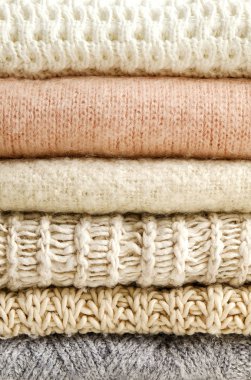 Bir sürü örülmüş pastel renkli süveter farklı örgü desenleri yığılmış, açıkça görülebilen doku. Şık sonbahar / kış mevsimi örgü giysileri. Kapat, metin için boşluk kopyala.