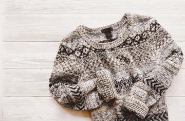 Moda kolay şık rahat tarzı büyük boyutlu kazak Beyaz ahşap dokulu masa arka plan üzerinde düğmeleri. Görünümü en iyi, yakın çekim, uzay kopyalayın. Şık kadın triko giyim ahşap yüzeyde yalan.