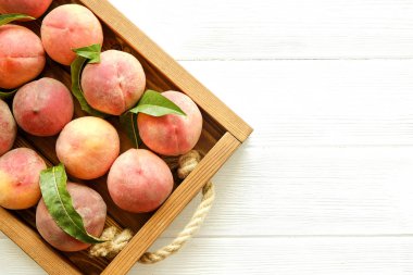Beyaz ahşap dokulu masa üzerinde ip kulplu ahşap tepsi tepsi üzerinde yığın olgun organik şeftali demet. Yerli malı hasat yığın. Temiz kavramı yeme. Arka plan, görünümü top, yakın çekim, alanı Kopyala.