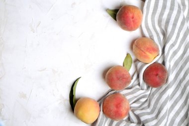 Beton yüzey masada beyaz kazık olgun organik şeftali demet. Yerli malı hasat öbek üzerinde vintage sıva tezgah, peçete. Temiz kavramı yeme. Alan arka plan, üstten görünüm Kopyala, yakın çekim