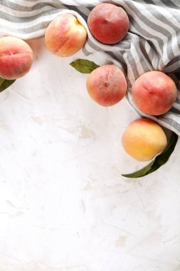 Beton yüzey masada beyaz kazık olgun organik şeftali demet. Yerli malı hasat öbek üzerinde vintage sıva tezgah, peçete. Temiz kavramı yeme. Alan arka plan, üstten görünüm Kopyala, yakın çekim