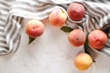 Beton yüzey masada beyaz kazık olgun organik şeftali demet. Yerli malı hasat öbek üzerinde vintage sıva tezgah, peçete. Temiz kavramı yeme. Alan arka plan, üstten görünüm Kopyala, yakın çekim