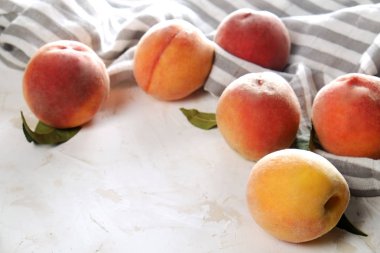 Beton yüzey masada beyaz kazık olgun organik şeftali demet. Yerli malı hasat öbek üzerinde vintage sıva tezgah, peçete. Temiz kavramı yeme. Alan arka plan, üstten görünüm Kopyala, yakın çekim