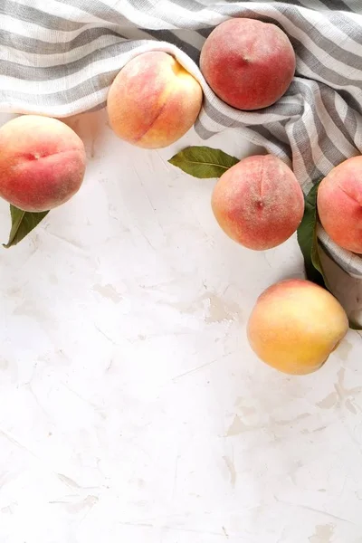 Beton yüzey masada beyaz kazık olgun organik şeftali demet. Yerli malı hasat öbek üzerinde vintage sıva tezgah, peçete. Temiz kavramı yeme. Alan arka plan, üstten görünüm Kopyala, yakın çekim