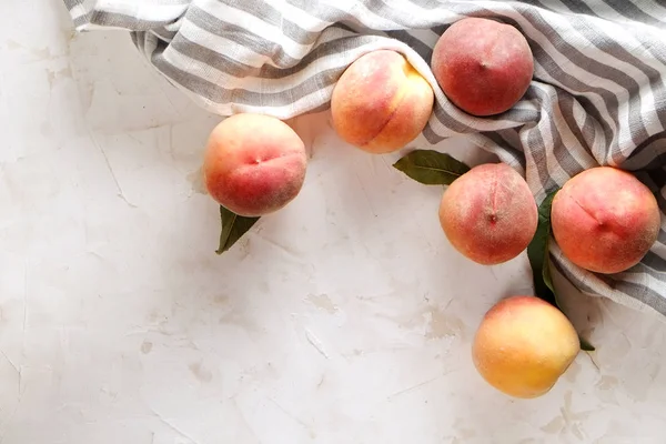 Beton yüzey masada beyaz kazık olgun organik şeftali demet. Yerli malı hasat öbek üzerinde vintage sıva tezgah, peçete. Temiz kavramı yeme. Alan arka plan, üstten görünüm Kopyala, yakın çekim