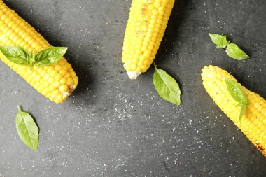 Yeşil fesleğen yaprakları ve karanlık taş masada tuz dekorasyon ile barbekü ateşe ızgara Mısır üç koçanı koydu. Temiz yemek alışkanlıkları kavramı. Arka plan, görünümü top, yakın çekim, yat, alanı Kopyala.