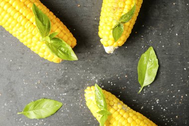 Yeşil fesleğen yaprakları ve karanlık taş masada tuz dekorasyon ile barbekü ateşe ızgara Mısır üç koçanı koydu. Temiz yemek alışkanlıkları kavramı. Arka plan, görünümü top, yakın çekim, yat, alanı Kopyala.