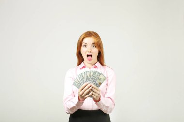 Avuç dolusu para demet yüz dolar faturaları fanı gibi holding ile yüzünü kaplayan genç güzel kızıl saçlı kadın. Tonla para heyecanlı çekici kadın var. Arka plan, kopya alanı, yakın çekim.