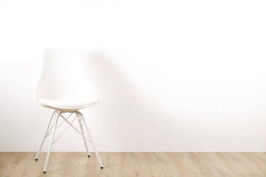 Boş odada, büyük boş duvar arka plan ahşap zemin üzerinde tek başına duran tek zarif beyaz loft tarzı sandalye. Metin için büyük kopya yer. Sadece bir boş koltuk. İnsan kaynakları kampanya kavramı işe.