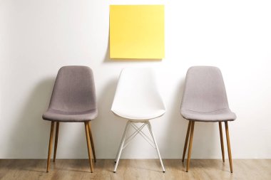 Üç kullanılabilir loft tarzı sandalye koltuk boş reklam afişi, beyaz duvar arka plan, sarı kopya alanı etiket için metin ile ahşap zemin üzerinde boş. Davet için boş pozisyon konsepti röportaj. Yakın çekim