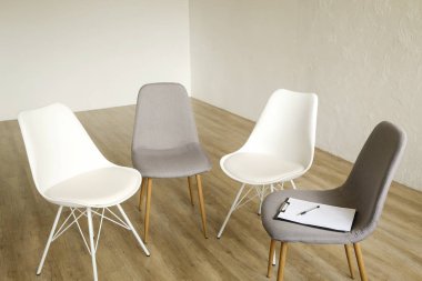 Birden çok loft tarzı boş sandalye ahşap zemin, danışmanının koltuk Pano ve notlar için kalem satırındaki ayakta. Grup terapisi için bağımlıları ve alkolikler konsept danışmanlık. Alan arka plan kopya, yakın çekim