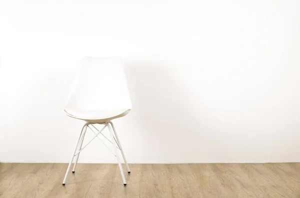 Single elegant white loft style chair standing alone on wooden floor in empty room, big blank wall background. Large copy space for text. Only one vacant seat. Human resources hiring campaign concept.