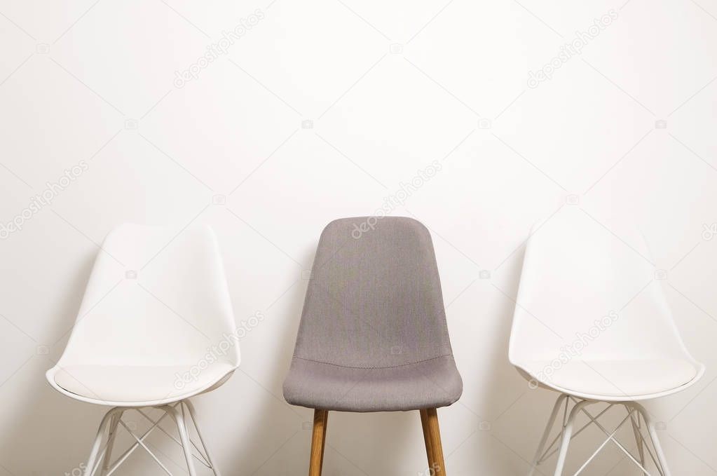 Multiple white gray elegant loft style empty chairs standing in room, wooden floor & big blank wall background with a lot of copy space for text. Vacant seats. Human resources hiring campaign concept