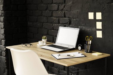Bir Blogger yaratıcı çalışma alanı. Beyaz dizüstü bilgisayar ve ahşap çatı stili ofiste siyah tuğla duvarlı tabloda katlanmış gözlükleri. Tasarımcının tablo kavramı. Yakın çekim, uzay, arka plan kopya.