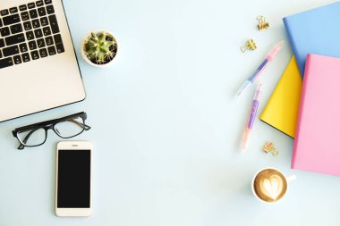 Ofis İşyeri dizüstü bilgisayar, birden çok renkli Notebook, boş ekran Mobil cep telefonu, kahve, sarf malzemeleri ve kırtasiye mavi zemin üzerine beyaz fincan ile. Yakın çekim, kopya alanı, üstten görünüm, düz lay.