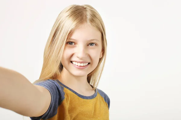 年轻美丽的少女的肖像与完美的微笑笑 手持手机在手中 快乐的年轻女子带着自拍与她的智能手机 孤立的白色背景 复制空间 — 图库照片