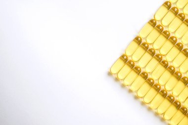 Omega 3 balık karaciğer yağı kapsülleri satırındaki desen arka plan oluşturan grup. Büyük altın yarı saydam hapları dokusuna yakın çekim. Sağlıklı her gün beslenme ek. Üstten görünüm, düz yatıyordu, kopya alanı.