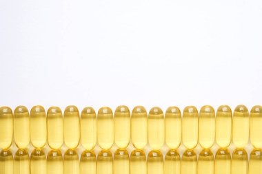 Omega 3 balık karaciğer yağı kapsülleri satırındaki desen arka plan oluşturan grup. Büyük altın yarı saydam hapları dokusuna yakın çekim. Sağlıklı her gün beslenme ek. Üstten görünüm, düz yatıyordu, kopya alanı.