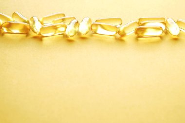 Omega 3 balık karaciğer yağı kapsülleri satırındaki desen arka plan oluşturan grup. Büyük altın yarı saydam hapları dokusuna yakın çekim. Sağlıklı her gün beslenme ek. Üstten görünüm, düz yatıyordu, kopya alanı.