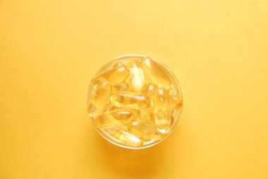 Omega 3 balık karaciğer yağı kapsülleri küçük cam kase içinde bir grup. Yığın altın yarı saydam hap kapatın. Her gün sağlıklı beslenme yağ asitleri dozaj ek. Üstten görünüm, düz yatıyordu, kopya alanı.