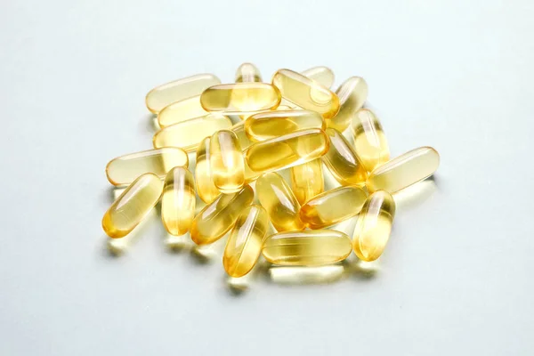 一束欧米茄3鱼肝油胶囊在成桩模式背景下 关闭大的金色半透明药丸质地 健康的每一天营养补充 顶部视图 平面放置 复制空间 — 图库照片