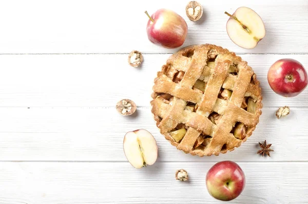 Traditional American Thanks Giving pie, whole & halved apples, cinnamon sticks, anise seeds. Homemade fruit tart baked to golden crust with ingredients. Close up, copy space, top view, background.