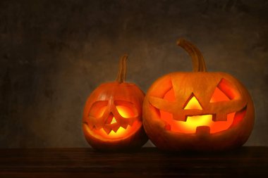 İçinde parlak ışık ile parlayan iki Halloween pumpkins korkunç ve komik Jack o fener karanlık mistik atmosferinde içine oyulmuş. Parti dekorasyon öznitelikleri. Arka plan, kopya alanı, yakın çekim.