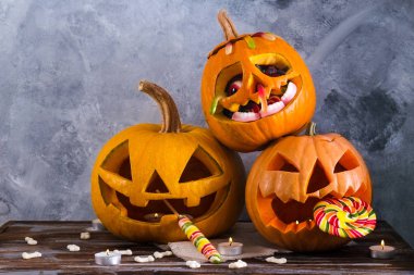 Farklı büyüklükte birkaç Turuncu kabak Jack o fener ahşap masa üzerinde oyulmuş. Arka plan, uzay kopyalayın, yakın çekim, görünümü top. Tüm eve Cadılar Bayramı partisi dekorasyon toplantı salonu. Ya parani ya canini kavramı.