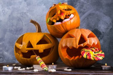 Farklı büyüklükte birkaç Turuncu kabak Jack o fener ahşap masa üzerinde oyulmuş. Arka plan, uzay kopyalayın, yakın çekim, görünümü top. Tüm eve Cadılar Bayramı partisi dekorasyon toplantı salonu. Ya parani ya canini kavramı.