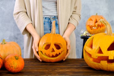 Genç kadının Jack O Lattern onun ahşap mutfak masasında bıçakla olgun Turuncu kabak oyma kapatın. Tüm hazırlama kadın Havva Halloween parti süslemeleri toplantı salonu. Arka plan, kopya alanı.