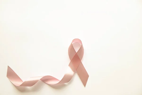 The pink colored ribbon - international symbol of breast cancer awareness and moral support for women. Isolated background, copy space, close up, top view fat lay.