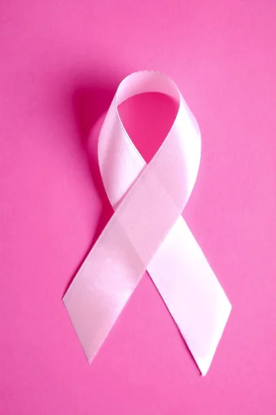 The pink colored ribbon - international symbol of breast cancer awareness and moral support for women. Isolated background, copy space, close up, top view fat lay.