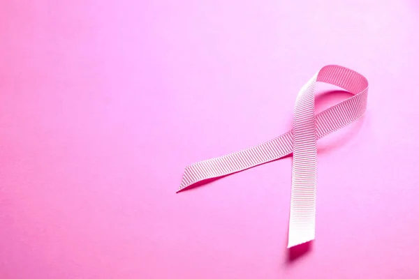 The pink colored ribbon - international symbol of breast cancer awareness and moral support for women. Isolated background, copy space, close up, top view fat lay.