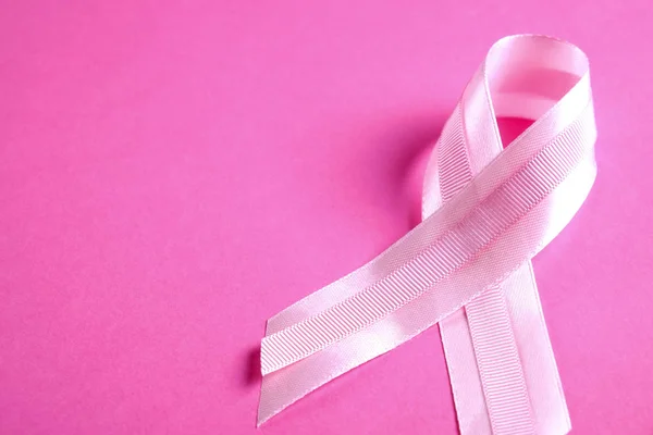 The pink colored ribbon - international symbol of breast cancer awareness and moral support for women. Isolated background, copy space, close up, top view fat lay.