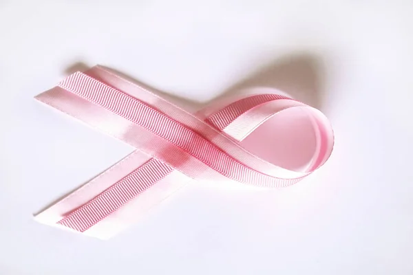 The pink colored ribbon - international symbol of breast cancer awareness and moral support for women. Isolated background, copy space, close up, top view fat lay.