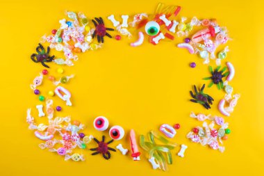 Çeşitli diş ve göz şeker şeklinde yayılan sarı arka plan, jöle örümcek, sakızlı solucanlar, şeker bones, yuvarlak lolipop ve diğer karışık şeker, kanlı parmak. Görünümü ana sayfa, yer kopyalayın, yakın çekim, yat