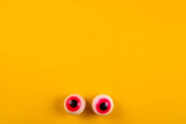 Parlak sarı zemin üzerine kırmızı öğrenciler ile şeker şeklinde göz küresi. Cadılar bayramı dekorasyonu kavramı. Uzay kopyalayın, üstten görünüm, düz yatıyordu yakın.