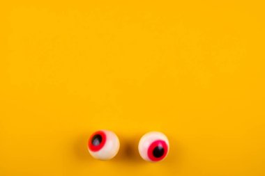 Parlak sarı zemin üzerine kırmızı öğrenciler ile şeker şeklinde göz küresi. Cadılar bayramı dekorasyonu kavramı. Uzay kopyalayın, üstten görünüm, düz yatıyordu yakın.